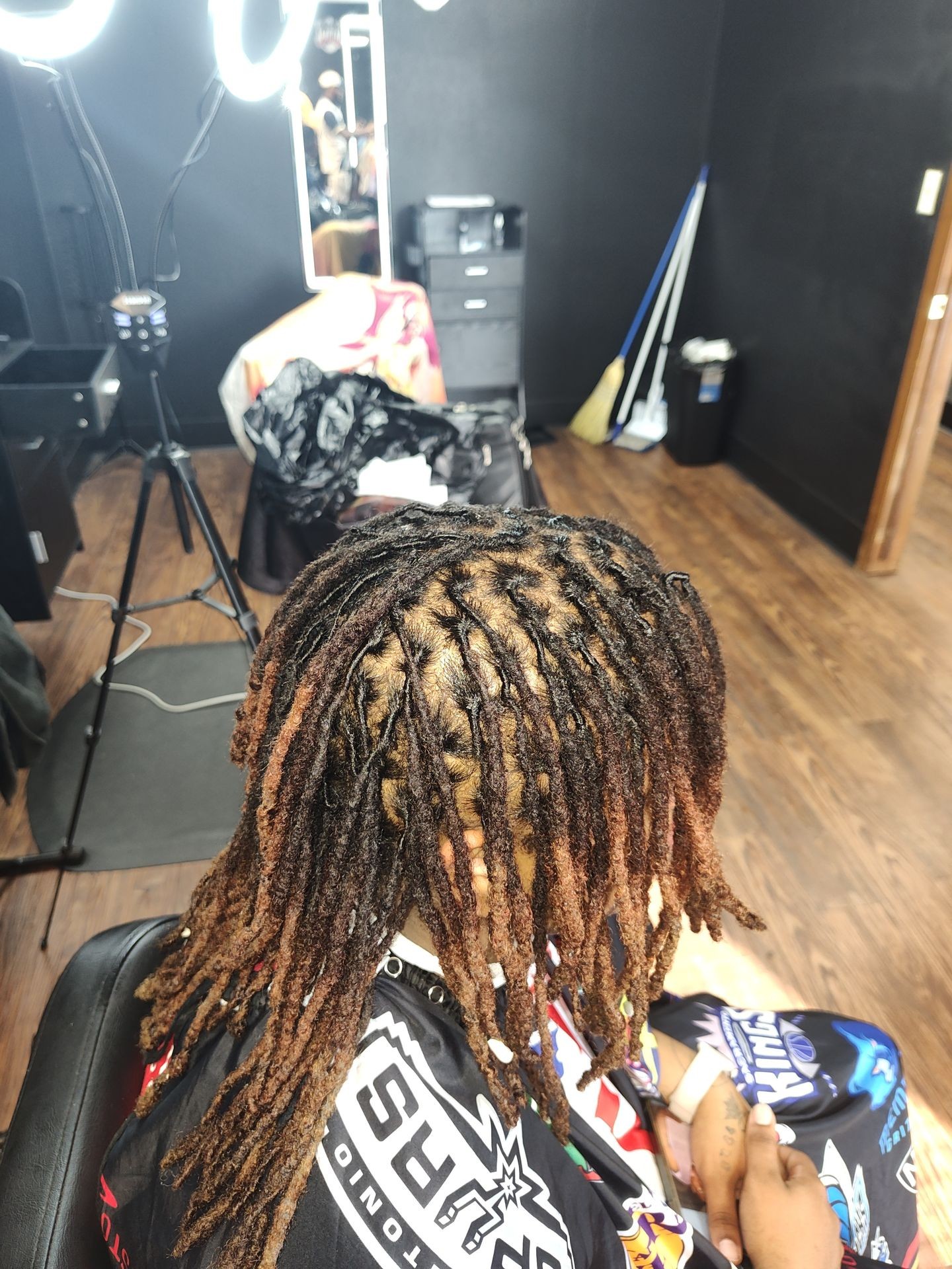 The image captures the artistry and care involved in a loc retwist, showcasing the meticulous process of maintaining and refreshing locs. Each loc is attentively separated, twisted, and secured at the roots to ensure a neat and uniform appearance. This method not only preserves the integrity of the locs but also promotes healthy hair growth and longevity.
